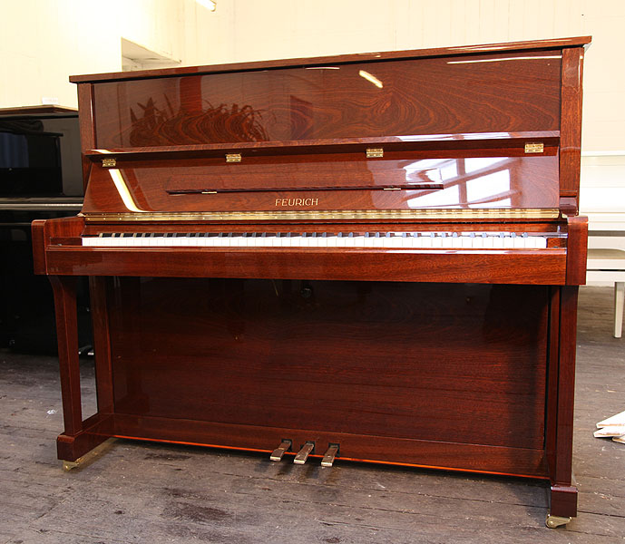 Brand new, Feurich Model 122 upright piano with a walnut case and brass fittings. Piano has an eighty-eight note keyboard and three pedals 