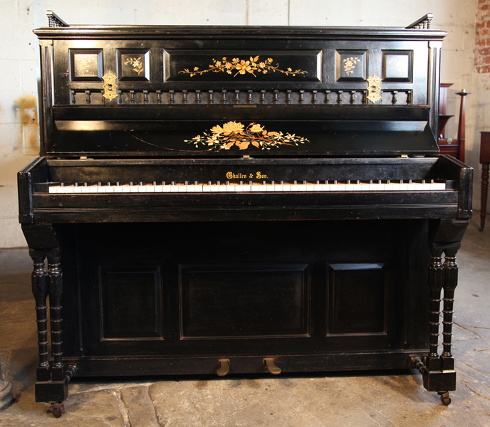 An 1884, Challen upright piano with a black case. Cabinet features spindles and floral decor on panels
