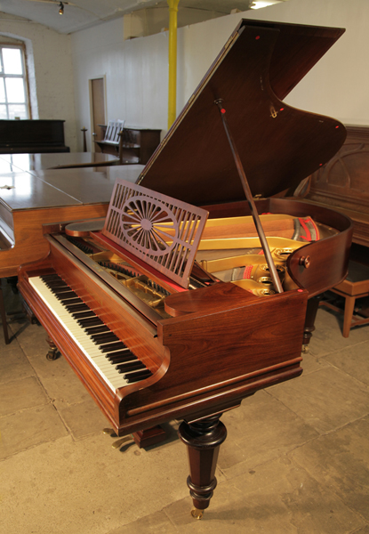 An antique, Bechstein Model A grand piano with a polished, rosewood case and turned legs. Piano has an eighty-five note keyboard and a two-pedal piano lyre.