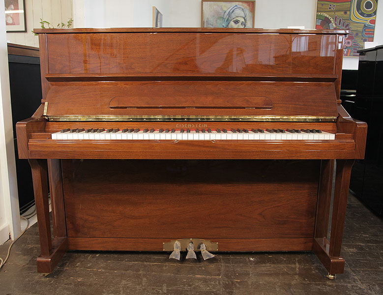 A brand new, Eisenstein UP121 upright piano with a walnut case and polyester finish. Keyboard lid features a slow-fall mechanism. Piano has an eighty-eight note keyboard and three pedals 