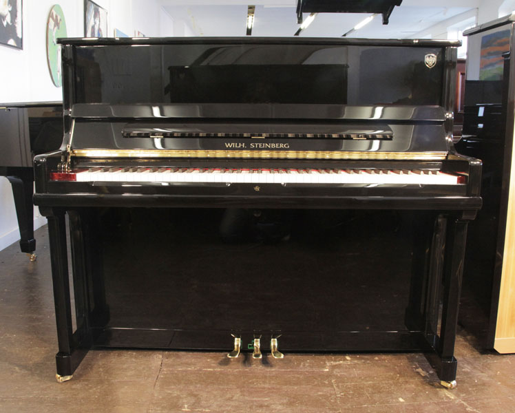 A brand new, Wilh Steinberg Model AT-K23 upright piano with a black case and brass fittings. Piano features a slow fall mechanism, eighty-eight note keyboard and three pedals. 