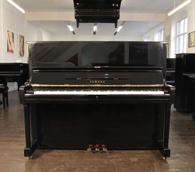 A 1986, Yamaha U1 upright piano with a black case and polyester finish. Piano has an eighty-eight note keyboard and three pedals.