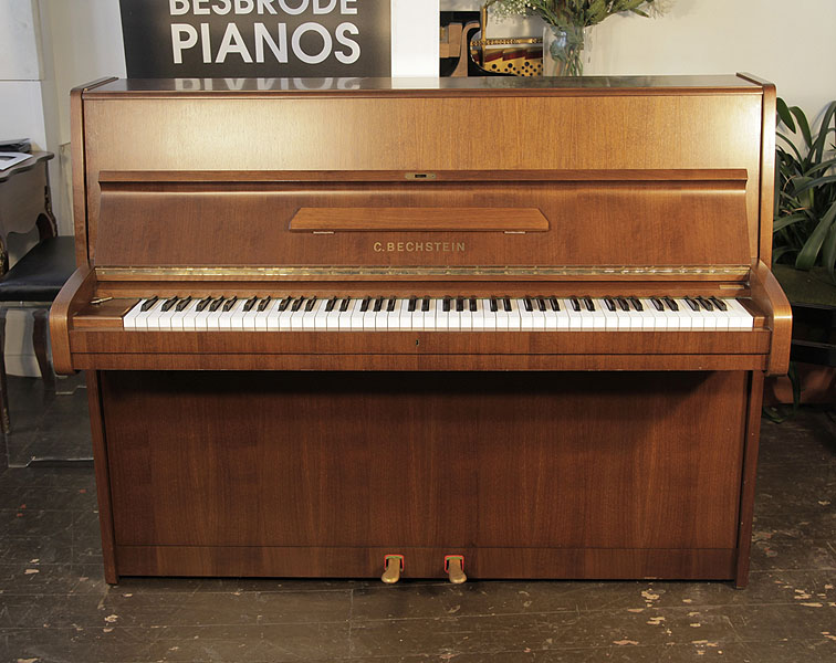 A 1982, Bechstein upright piano with a satin, mahogany case. Piano has an eighty-eight note keyboard and two pedals.