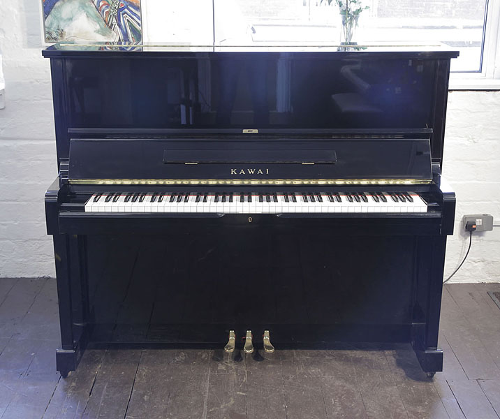 Reconditioned, 1991, Kawai SU-2L upright piano with a black case and brass fittings. Piano has an eighty-eight note keyboard and three pedals. 