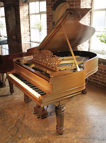 A 1900, Steinway Model A grand piano with a walnut case, filigree music desk and fluted, barrel legs with gadrooning detail.