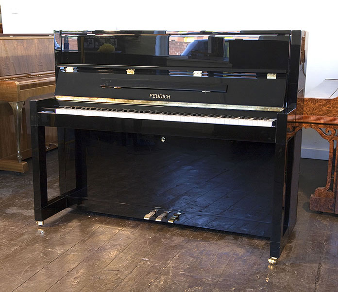Brand new, Bauhaus style, Feurich Model 115 Premiere upright piano with a black case and polyester finish. Bauhaus style represented in the minimal, geometric style of the piano cabinet. Piano has an eighty-eight note keyboard and a three-pedal piano lyre. 