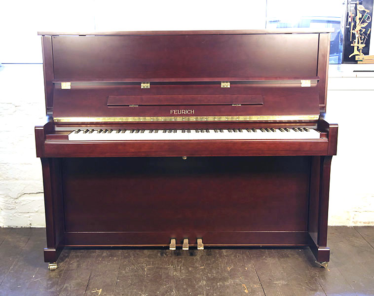 Brand new, Feurich Model 122 upright piano with a satin, mahogany case and brass fittings. Piano has an eighty-eight note keyboard and three pedals 