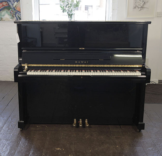 A 1987, Kawai BS-30 upright piano with a black case and polyester finish. Piano has an eighty-eight note keyboard and three pedals.