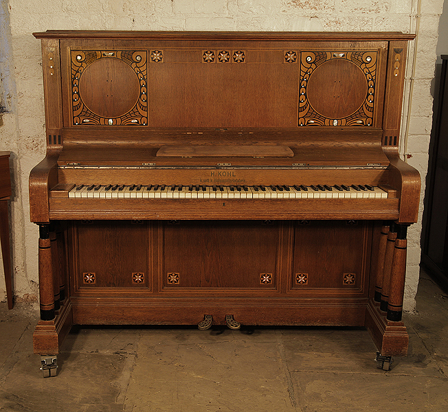 A Kohl upright piano for sale with a walnut case and three turned, column legs. Entire cabinet inlaid with contrasting ebony and mother of pearl in a stylised floral design Piano has an eighty-five note keyboard and two pedals. 