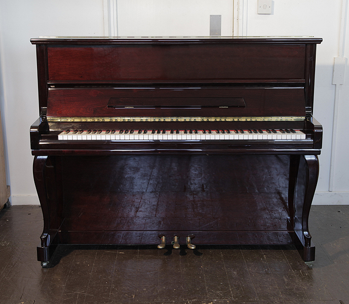 A Samick upright piano with a mahogany case and cabriole legs. Piano has an eighty-eight note keyboard and three pedals 