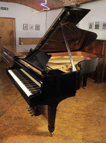 A 1974, Steinway Model B grand piano with a black case and spade legs. Piano has a three-pedal lyre and an eighty-eight note keyboard.