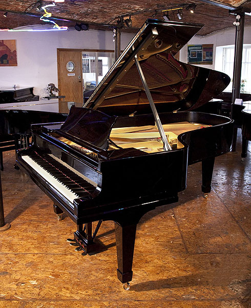 A 1925, Steinway Model C grand piano with a black case and spade legs. Piano has an eighty-eight note keyboard and a three-pedal lyre.