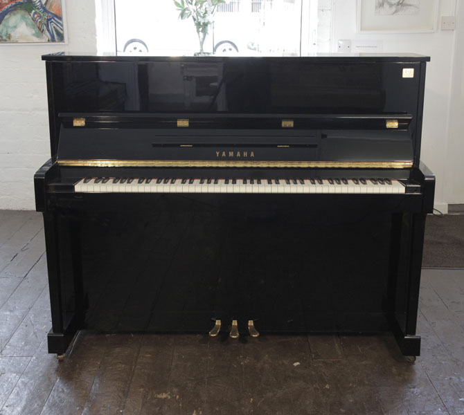 Reconditioned,  Yamaha ET121 upright piano for sale with a black case and brass fittings. Piano has an eighty-eight note keyboard and three pedals..
