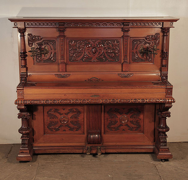 Neoclassical, Hupfer upright piano for sale with an ornately carved, mahogany case and turned, legs. Piano has an eighty-five note keyboard and two pedals.