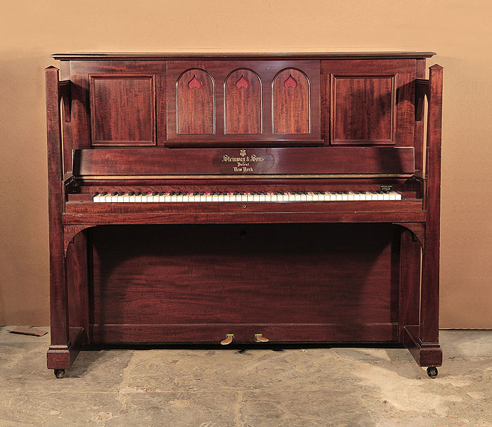Arts and Crafts, 1905, Steinway upright piano for sale with a figured, mahogany case and large sculptural legs. Piano has an eighty-eight note keyboard and two pedals. 