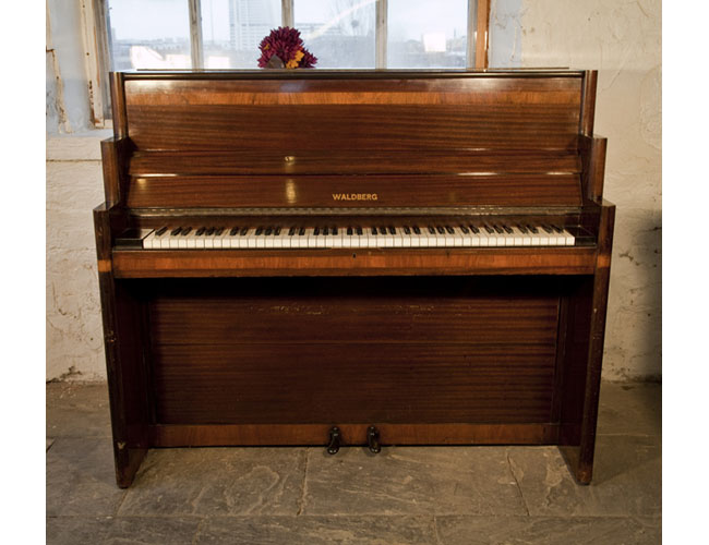 Art-Deco style, Waldberg upright piano with a polished, mahogany case. Cabinet features geometric styling and banded inlay