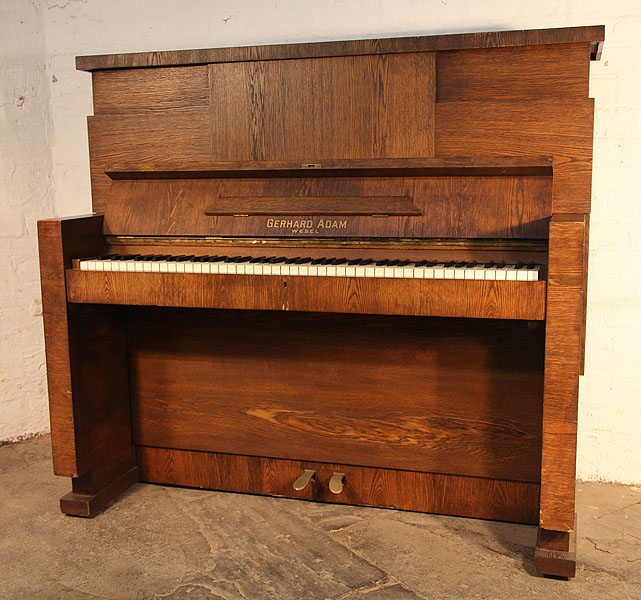 Gerhard Adams upright piano with a Modernist, Oak Case. Piano has an eighty-five note keyboard and a two-pedal piano lyre.
