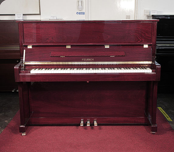 Brand new, Feurich Model 122 upright piano with a mahogany case and brass fittings. Piano features a slow fall mechanism. Piano has an eighty-eight note keyboard and three pedals. 