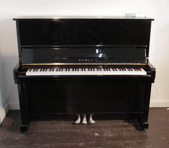 Piano for sale. A Kawai KU-1B upright piano with a black case and polyester finish. Piano has an eighty-eight note keyboard and three pedals. 