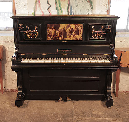 A 1905, Brinsmead upright piano with a polished, black case and central panel featuring a crystoleum image of a Classical scene.  Piano has an eighty-five note keyboard and two pedals.