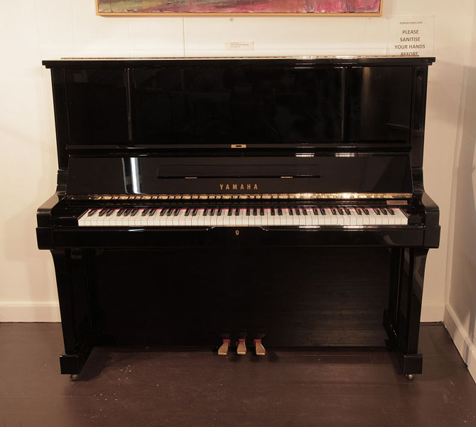 Reconditioned, 1987, Yamaha UX-3 upright piano for sale with a black case and brass fittings. Piano has an eighty-eight note keyboard and three pedals. 