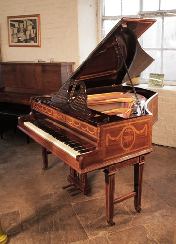 A 1903, Broadwood grand piano with a rosewood case and gate legs. Cabinet inlaid with swags, bows and panels of musical instruments.Piano has an eighty-five note keyboard and a two-pedal lyre