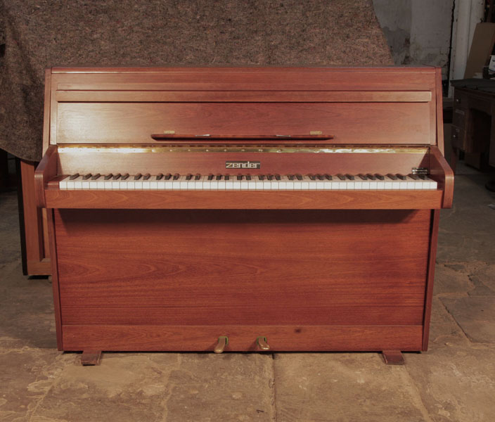 Pre-owned Zender upright piano with a polished, walnut case and brass fittings. Piano has an eighty-five note keyboard and two pedals.