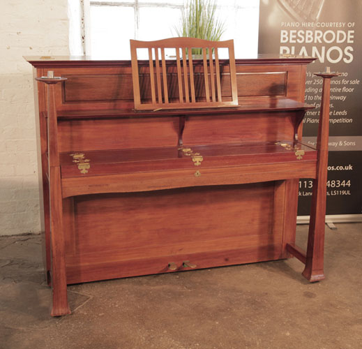Arts and Crafts style, 1899, Bechstein model IV upright piano with a walnut case and candlesticks that sit on top of the legs. Cabinet features sizeable, brass hinges. Design by Walter Cave. Piano has an eighty-five note keyboard and two pedals.