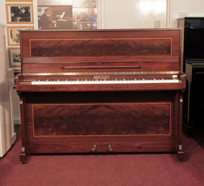 Reconditioned, 1988, Bentley upright piano with a mahogany case with flame mahogany panels bordered with satinwood stringing. Piano has an eighty-eight note keyboard and two pedals.