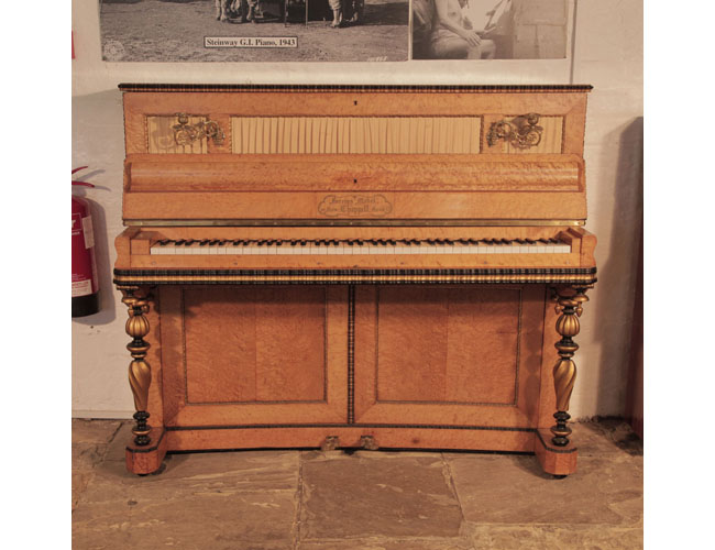 An 1860's, Chappell upright piano with a French style, bird's eye maple case and twisted, baluster legs.  The cut-out front panels are backed in pleated, gold fabric. Cabinet features gilt and black accents. 