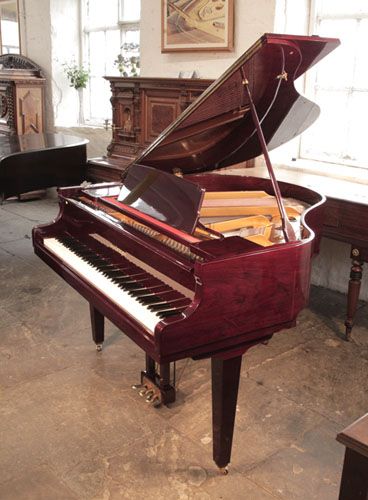 A 1990,  Hyundai G-50A baby grand piano with a cherry mahogany case and square, tapered legs. Piano has an eighty-eight note keyboard and a three-pedal lyre. 
