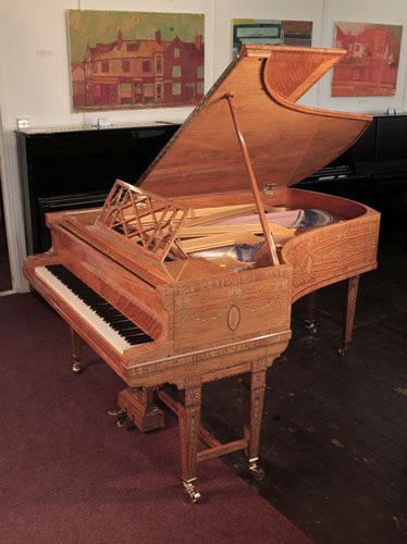 A 1911, Bluthner grand piano with a quarter cut, satinwood case with boxwood stringing inlay. Entire cabinet inlaid with swagged bellflowers, secured with bows. Piano has gate legs attached with a cross stretcher.