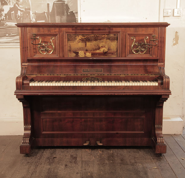 A 1905, Brinsmead upright piano with a polished, rosewood case and central panel featuring a crystoleum image of a Pre Raphaelite scene.  Piano has an eighty-five note keyboard and two pedals.