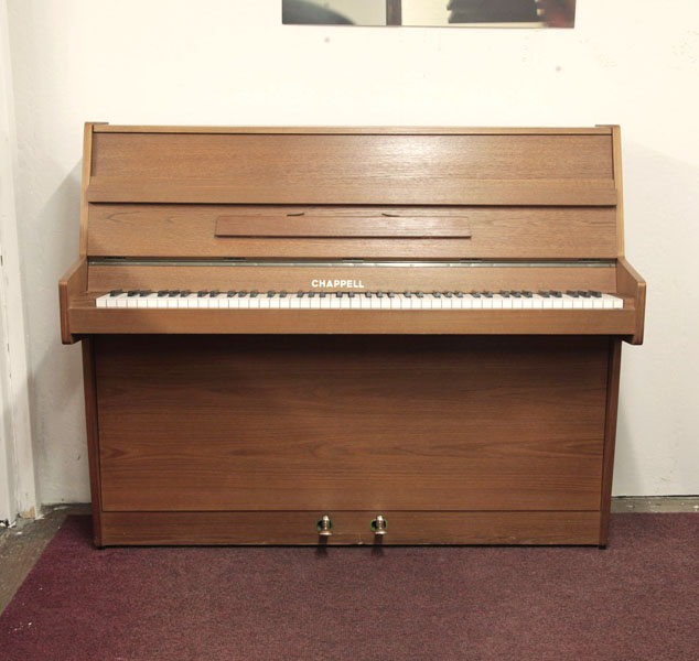 Pre-owned, Chappell upright piano with a walnut case. Piano has an eighty-eight note keyboard and two pedals.