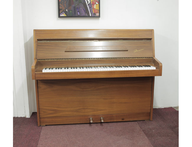 British made, 1977, Danemann upright piano with a walnut case and Schwander action. Piano has an eighty-eight note keyboard and two pedals